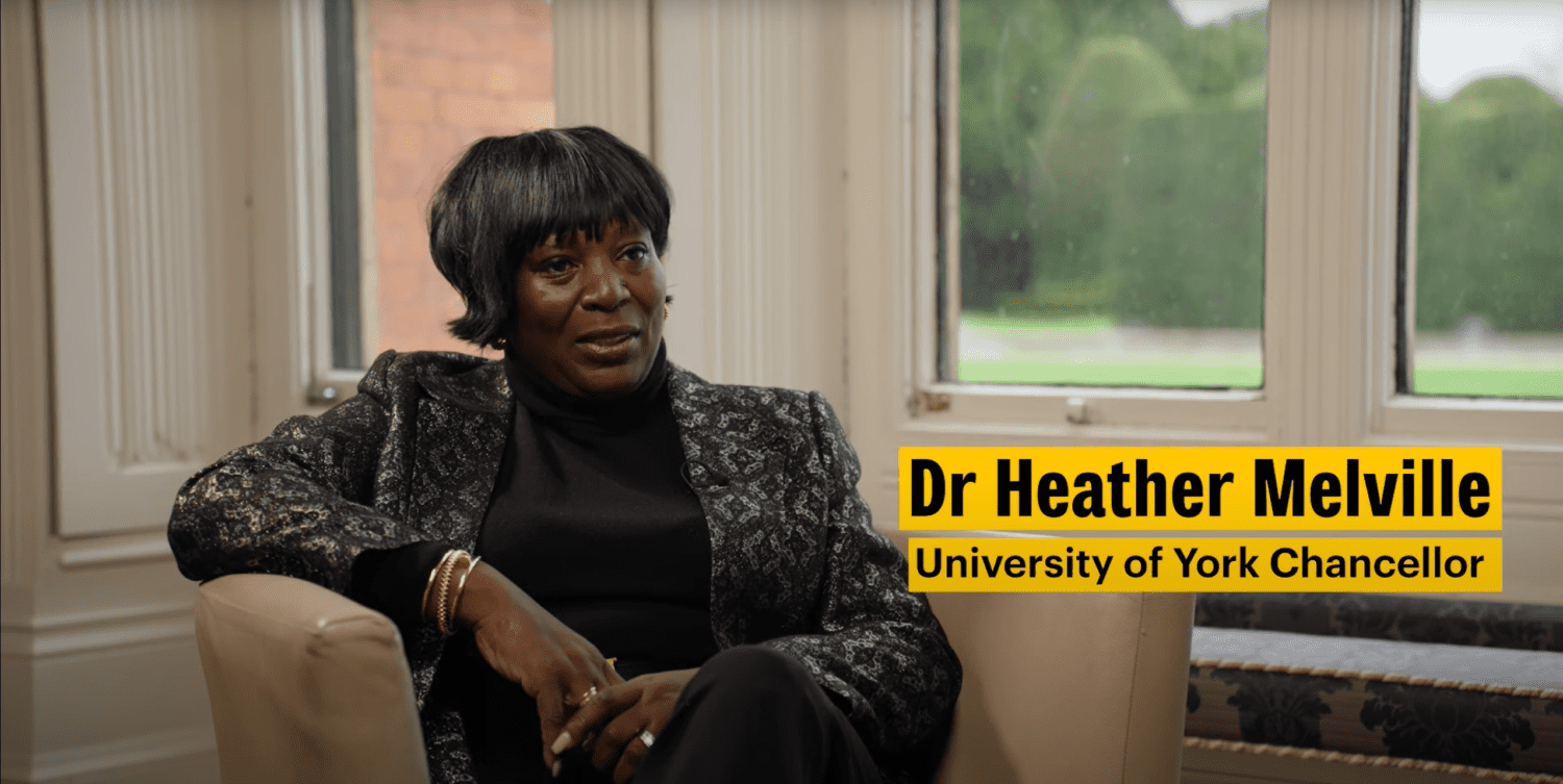 Dr Heather Melville sitting down with text that reads "Dr Heather Melville, University of York Chancellor"